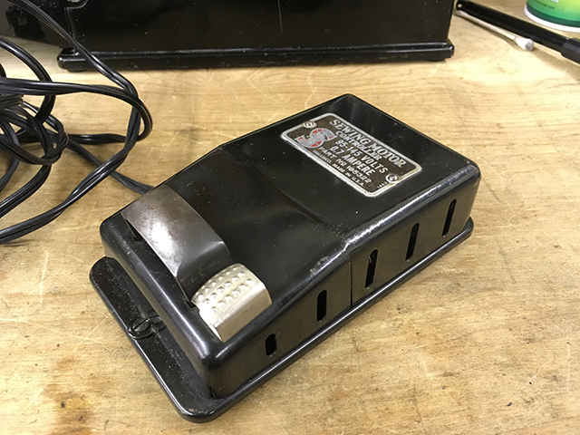 A sewing machine foot controller made of black painted steel. The nameplate reads, "SEWING MOTOR CONTROLLER / 95–145 VOLTS / 0.7 AMPERE / PART NO. 195322 / SIMANCO MADE IN U.S.A."