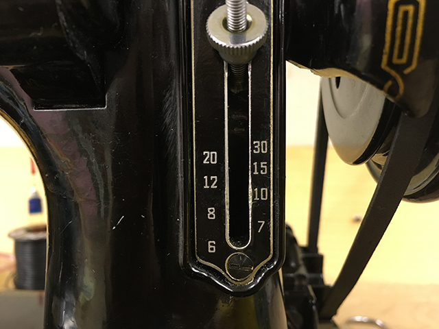 A closeup of the stitch regulator lever, showing the numbers 30, 20, 15, 12, 10, 8, 7, and 6.
